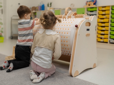 Dzieci grają z edukacyjną planszą z guzikami