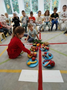 Dzieci sortują owoce i warzywa na talerzach w klasie