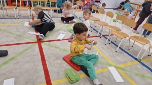 Dzieci siedzą na podłodze w klasie, robiąc ćwiczenia