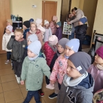 Grupa dzieci w czapkach i kurtkach w pomieszczeniu