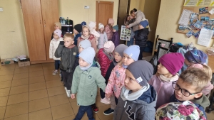 Grupa dzieci w czapkach i kurtkach w pomieszczeniu