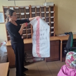 Kobieta trzyma worki z napisem "Poczta Polska" w biurze pocztowym