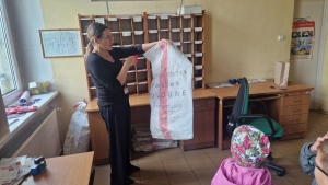 Kobieta trzyma worki z napisem "Poczta Polska" w biurze pocztowym