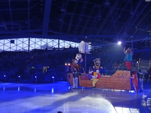 Postacie w kostiumach na lodowisku w hali sportowej