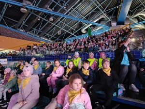 Grupa dzieci i dorosłych na trybunach w hali sportowej
