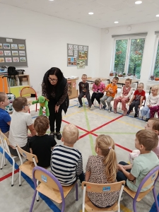 Nauczycielka z zabawką w ręku prowadzi zajęcia z dziećmi