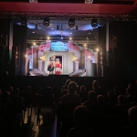 Widownia teatralna z widzami i sceną z dekoracjami