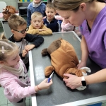 Dzieci i kobieta badają pluszowego psa na stole