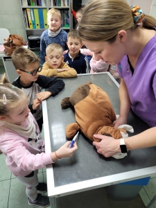 Dzieci i kobieta badają pluszowego psa na stole