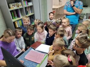 Grupa dzieci w szkole patrzy na komputer z nauczycielem