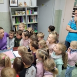 Grupa dzieci w przedszkolu słucha opowieści od dwóch dorosłych