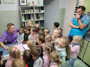 Grupa dzieci w przedszkolu słucha opowieści od dwóch dorosłych