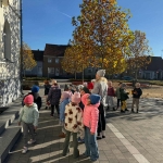 Grupa dzieci z opiekunką na spacerze w parku jesienią