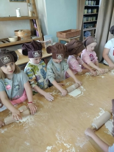 Dzieci w czapkach kuchennych robią ciasto na stole