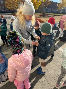 Kobieta w czapce daje dziecku w zimowej czapce coś do ręki. (49 znaków)