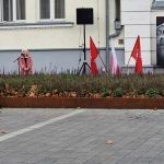 Kobieta mówi do mikrofonu na ulicy obok budynku. (Wykorzystano 49 znaków)