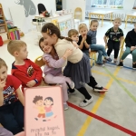 Dzieci siedzą w klasie, jedna dziewczynka obejmuje koleżankę