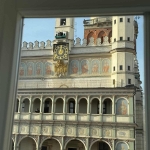 Widok na ratusz z okna, z zegarem i freskami na fasadzie