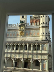 Widok na ratusz z okna, z zegarem i freskami na fasadzie