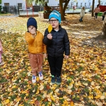 Dwóch chłopców stoi na liściach w parku jesienią