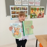 Dziewczynka trzyma dwie książki w klasie przed tablicą