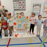 Grupa dzieci trzyma duży rysunek w przedszkolu