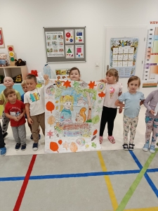 Grupa dzieci trzyma duży rysunek w przedszkolu