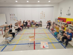 Dzieci siedzą na krzesłach w sali lekcyjnej, ucząc się gry