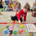 Dzieci w przedszkolu obserwują eksperyment z kolorowymi płynami