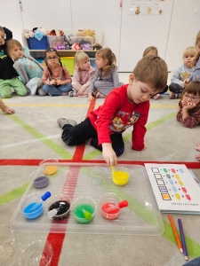 Dzieci w przedszkolu obserwują eksperyment z kolorowymi płynami