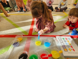 Dzieci bawią się kolorowymi płynami na podłodze