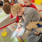 Dzieci w przedszkolu malują obrazki na podłodze