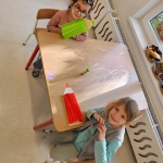 Dwie dziewczynki siedzą przy stole z dużymi ołówkami