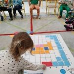 Dzieci w przedszkolu grają w grę planszową na podłodze
