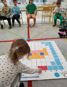 Dzieci w przedszkolu grają w grę planszową na podłodze