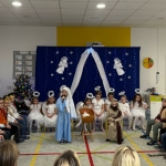 Dzieci w kostiumach występują na scenie w szkolnej sali
