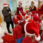 Grupa dzieci i dorosłych w czapkach Mikołaja podczas świątecznej zabawy