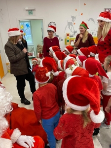 Grupa dzieci i dorosłych w czapkach Mikołaja podczas świątecznej zabawy