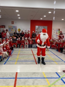 Santa Claus stoi przed grupą dzieci w strojach świątecznych
