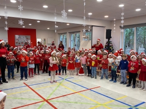 Grupa dzieci w czerwonych ubraniach i czapkach Mikołaja podczas występu