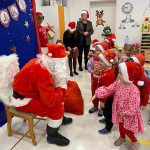 Dzieci w strojach świątecznych rozmawiają z Mikołajem