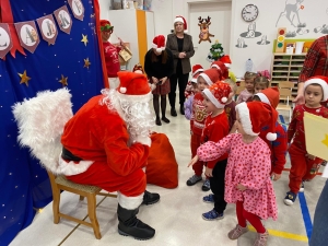 Dzieci w strojach świątecznych rozmawiają z Mikołajem
