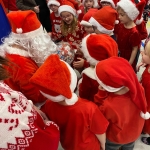 Grupa dzieci w czerwonych czapkach z Mikołajem