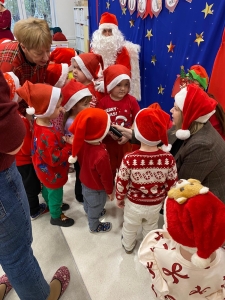 Dzieci w czapkach Mikołaja z Santa Clausem na tle