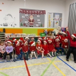 Grupa dzieci w czapkach Mikołaja z nauczycielką w klasie