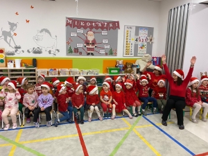 Grupa dzieci w czapkach Mikołaja z nauczycielką w klasie