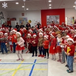 Dzieci w czapkach Mikołaja śpiewają w szkolnej sali