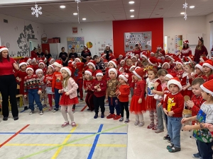 Dzieci w czapkach Mikołaja śpiewają w szkolnej sali