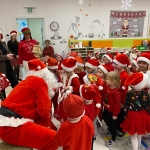 Dzieci w czapkach Mikołaja spotykają się z Mikołajem w szkole
