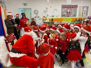Dzieci w czapkach Mikołaja spotykają się z Mikołajem w szkole